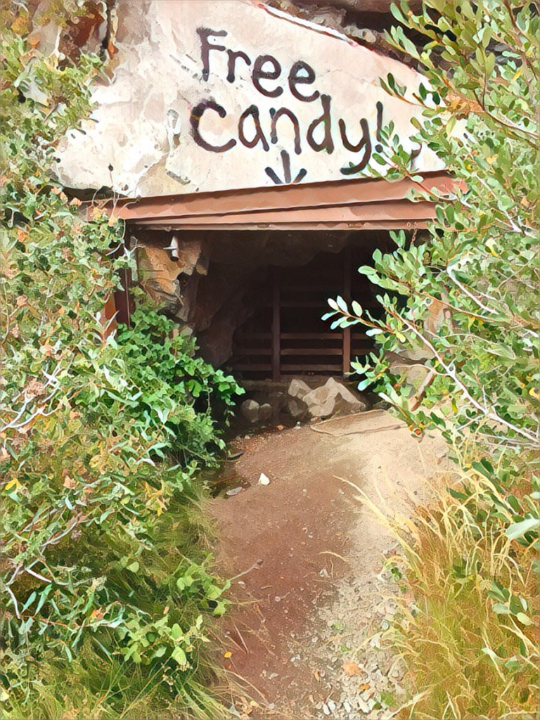 An ominous, dark opening to an abandoned mine with the words “Free Candy” spray painted above.